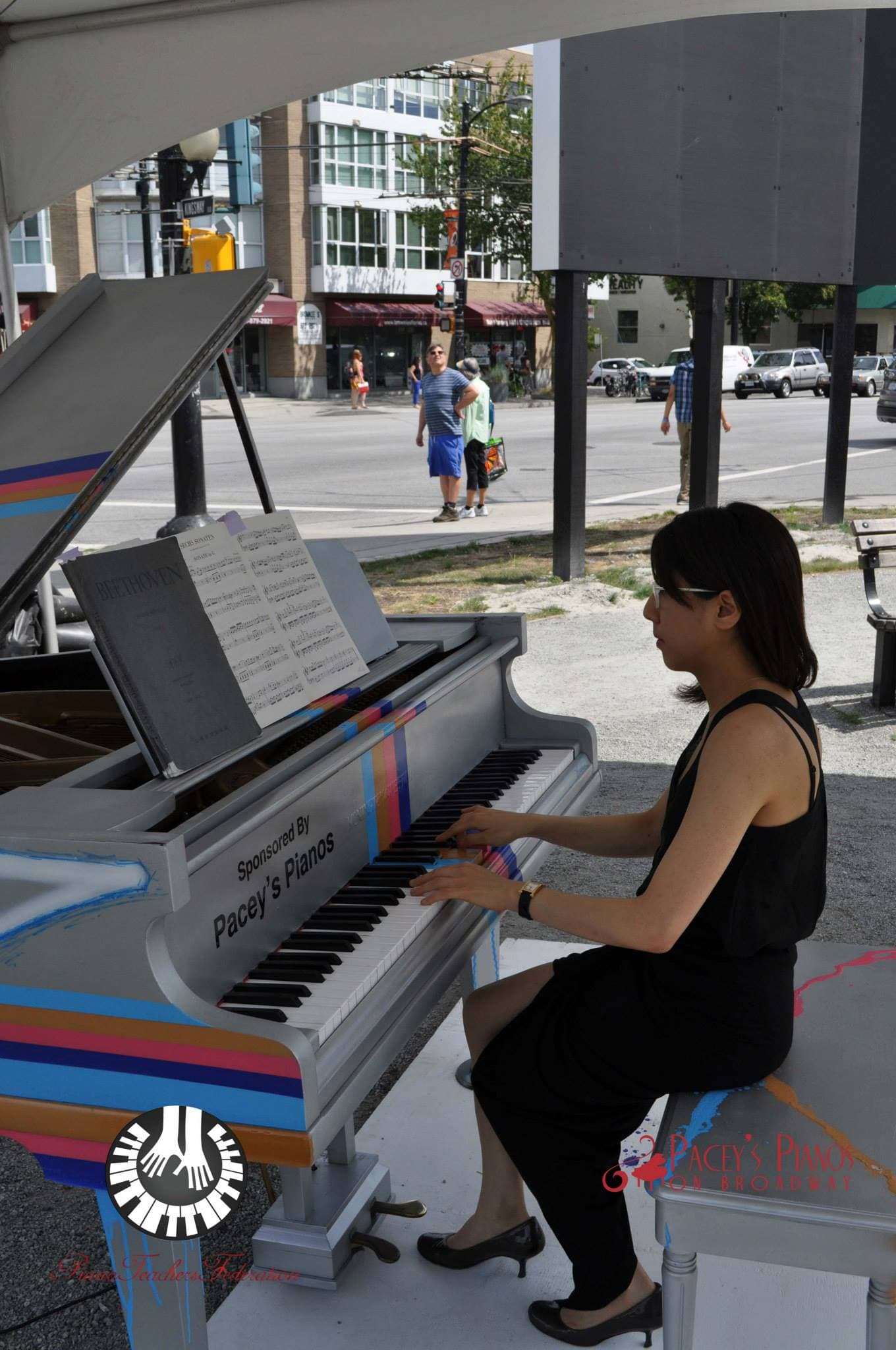 Beethoven from sheet music on a silver baby grand striped with pink, orange and blue racing lines, beside busy Kingsway.