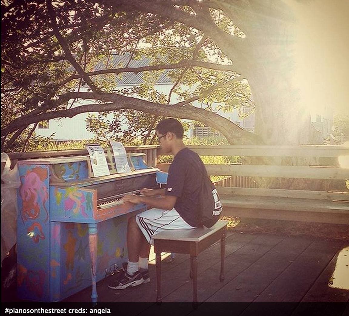 Low golden sun floods a boardwalk as a teenager plays a pastel sea-creature piano. The last song of the day.